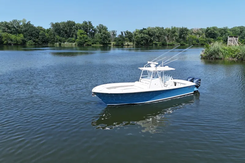 Slide: The Image of A blue and white 2010 Regulator 34SS floats on a calm lake, surrounded by trees. - 10