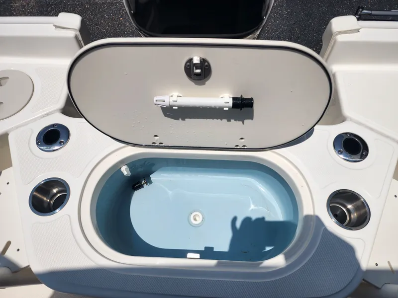 Slide: The Image of An open storage compartment on a Boston Whaler 150 Montauk boat, surrounded by cup holders. - 13