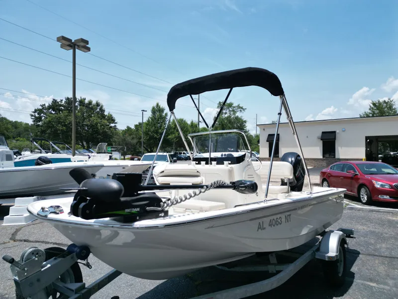 Slide: The Image of A 2023 Boston Whaler 150 Montauk with a black Bimini top sits on a trailer in a parking lot. - 20