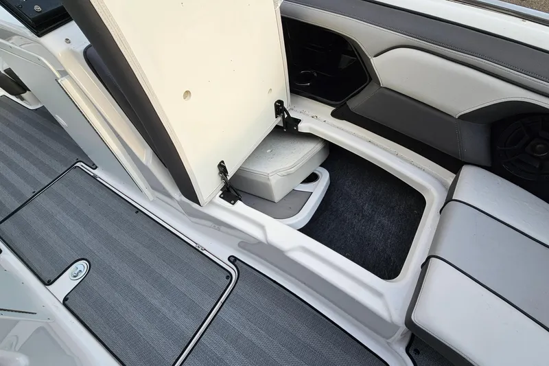 Slide: The Image of 2019 Yamaha Boats 212 Limited interior storage compartment with open seat and carpeted flooring. - 25