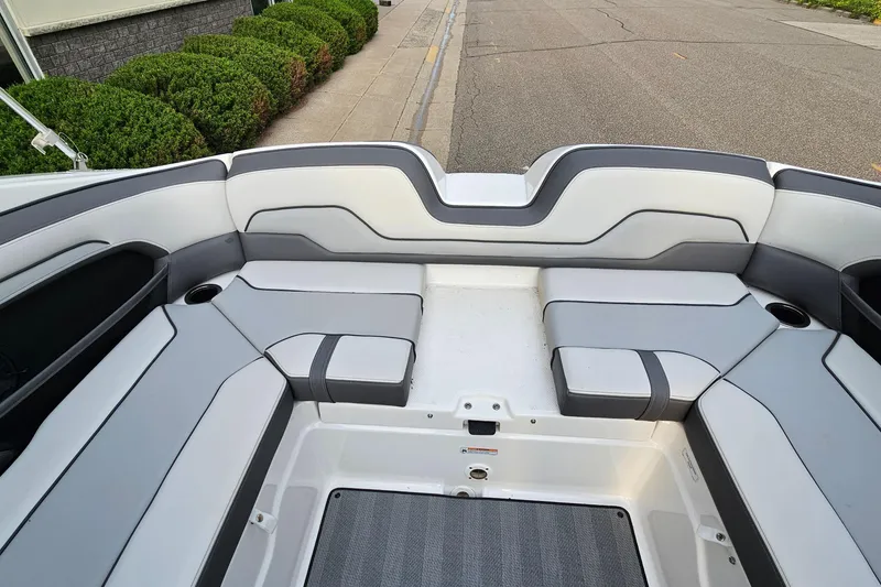 Slide: The Image of 2019 Yamaha Boats 212 Limited interior with gray and white seating, docked on a street. - 27