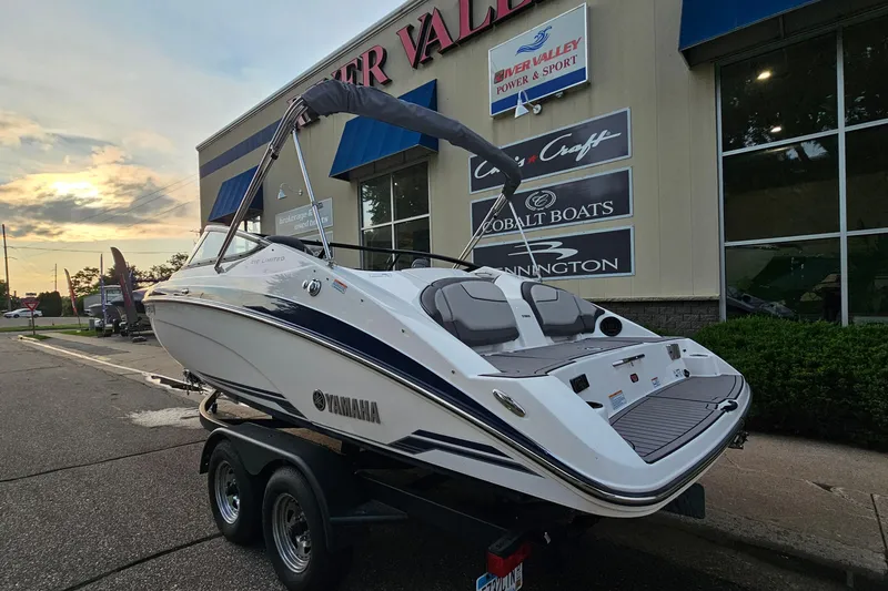 Slide: The Image of 2019 Yamaha Boats 212 Limited on trailer at dealership, sunset in background. - 2