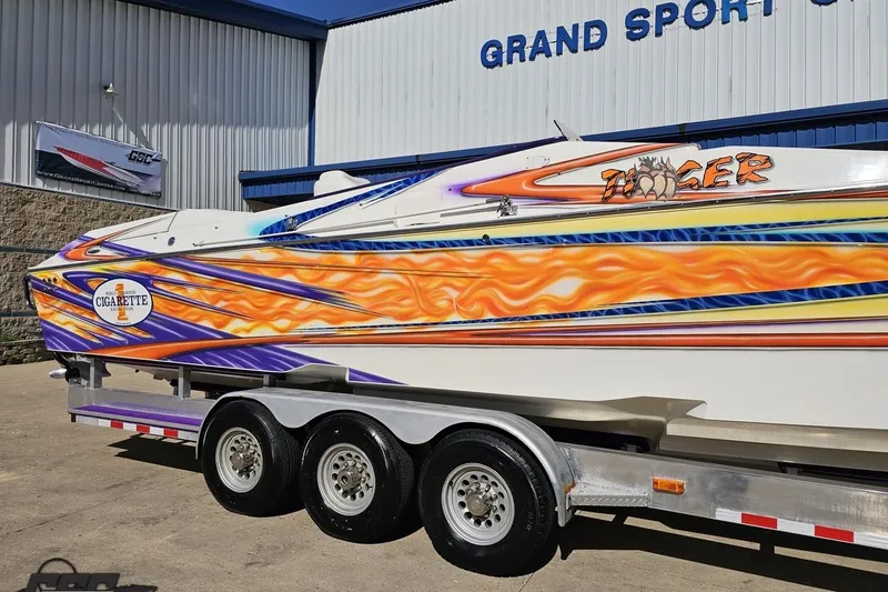 Slide: The Image of 2002 Cigarette 42' Tiger boat with vibrant flame graphics on a trailer. - 6