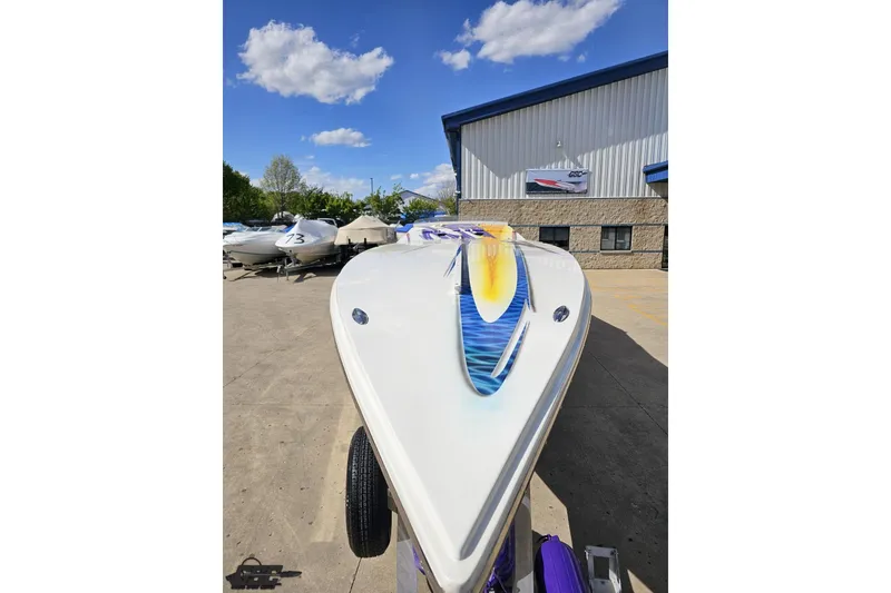 Slide: The Image of 2002 Cigarette 42' Tiger boat with vibrant graphics, parked outdoors under a clear sky. - 18