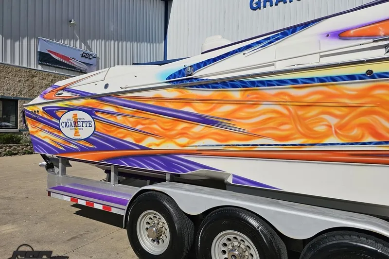 Slide: The Image of 2002 Cigarette 42' Tiger boat with vibrant flame graphics on a trailer. - 7