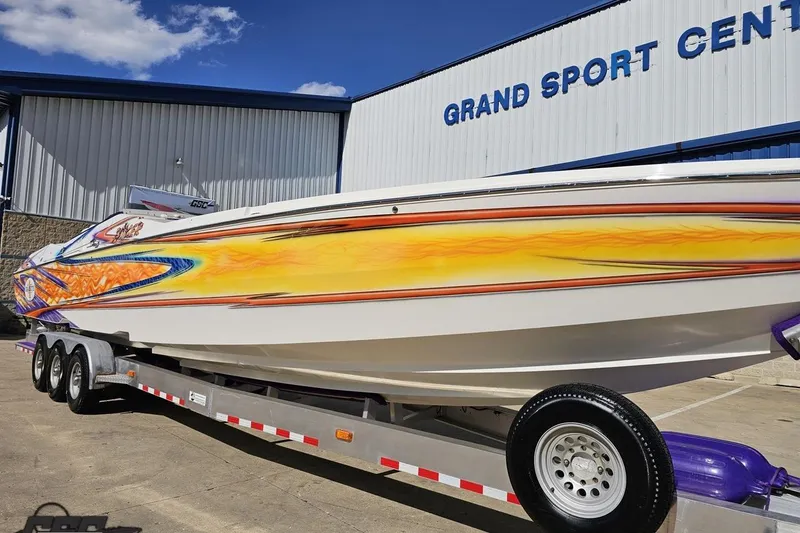 Slide: The Image of 2002 Cigarette 42' Tiger boat with vibrant graphics on a trailer at Grand Sport Center. - 16