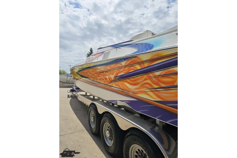 Slide: The Image of 2002 Cigarette 42' Tiger boat with vibrant flame graphics on a trailer. - 31