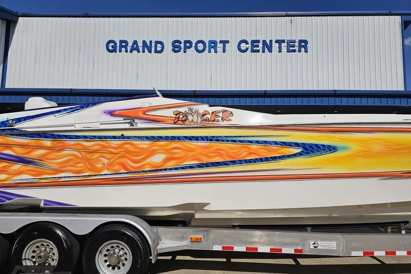 Slide: The Image of 2002 Cigarette 42' Tiger boat with vibrant flame graphics at Grand Sport Center. - 4
