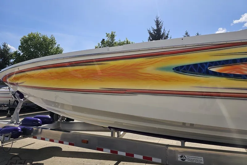 Slide: The Image of 2002 Cigarette 42' Tiger boat with vibrant flame graphics on trailer. - 23