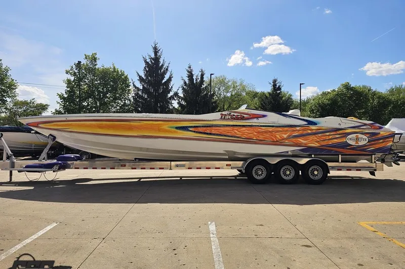 Slide: The Image of 2002 Cigarette 42' Tiger speedboat with vibrant custom paint on a trailer, parked outdoors. - 25