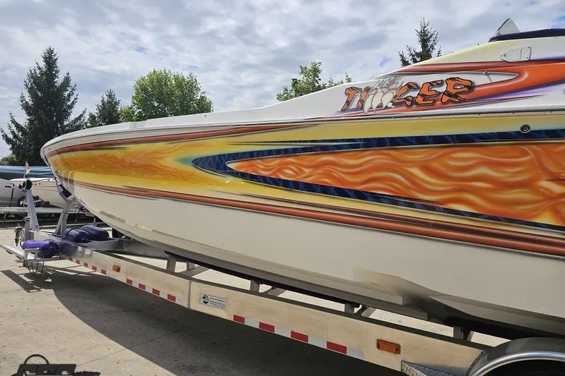 Slide: The Image of 2002 Cigarette 42' Tiger boat with vibrant flame graphics on a trailer. - 30