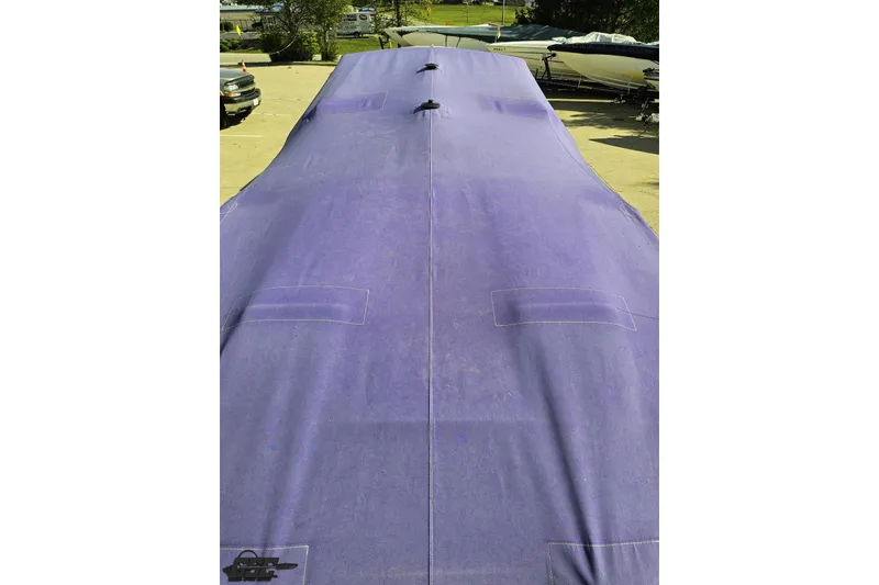 Slide: The Image of Covered 2002 Cigarette 42' Tiger boat with a purple tarp in a parking area. - 101