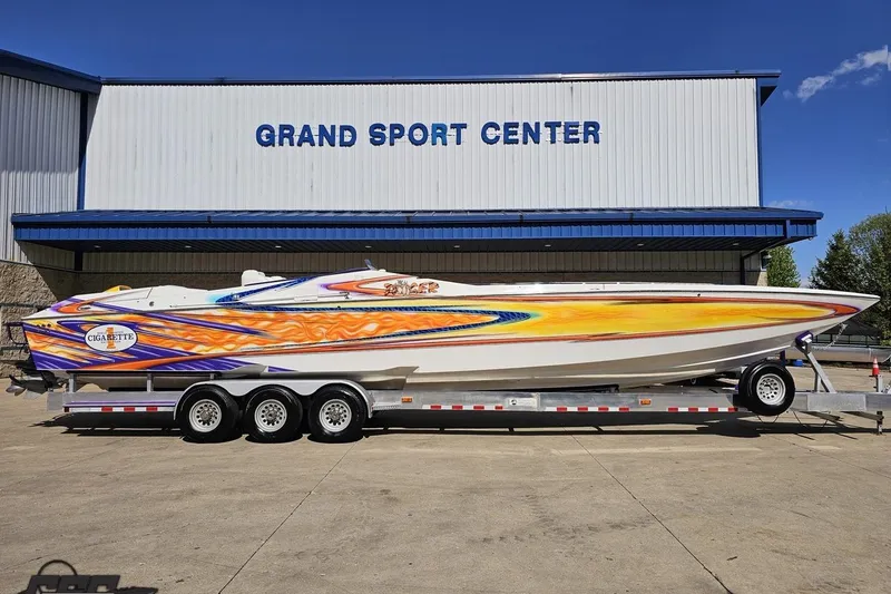 Slide: The Image of 2002 Cigarette 42' Tiger boat with vibrant graphics on a trailer at Grand Sport Center. - 2