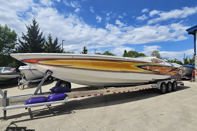 Slide: The Image of 2002 Cigarette 42' Tiger speedboat on trailer, vibrant custom paint, clear sky background. - 20