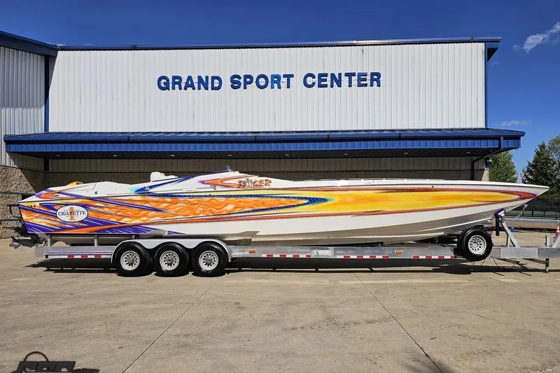 The Image of 2002 Cigarette 42' Tiger boat with vibrant graphics on a trailer at Grand Sport Center. - 1