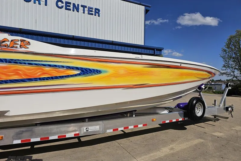Slide: The Image of 2002 Cigarette 42' Tiger boat with vibrant flame graphics on a trailer. - 5