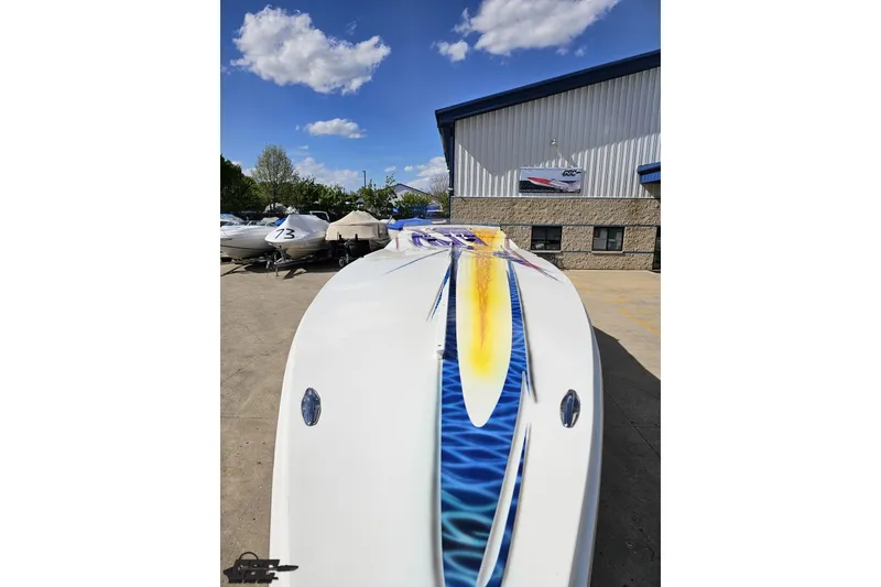 Slide: The Image of 2002 Cigarette 42' Tiger boat with vibrant graphics, parked outdoors under a blue sky. - 19