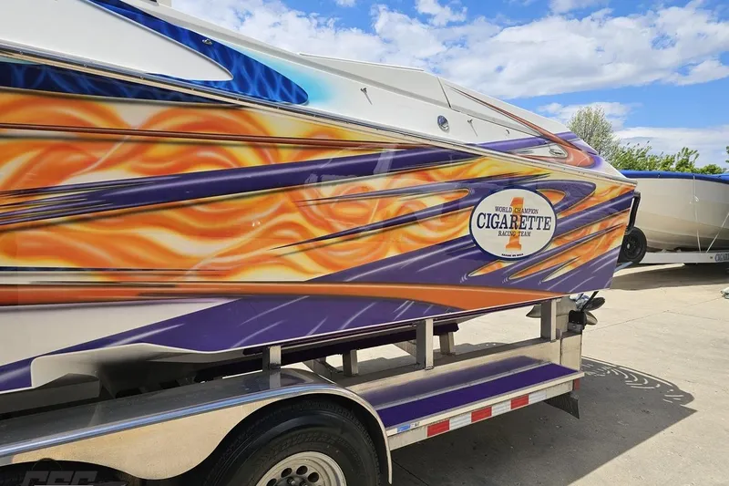 Slide: The Image of 2002 Cigarette 42' Tiger boat with vibrant flame graphics on a trailer. - 28