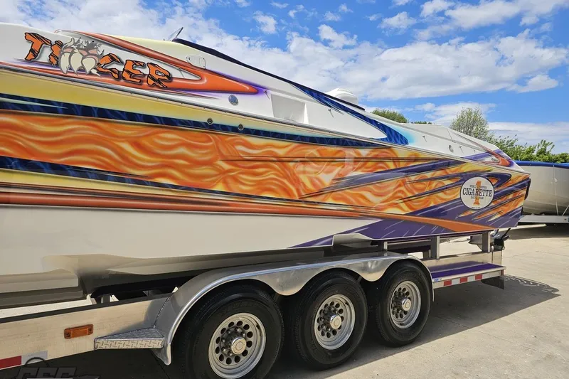 Slide: The Image of 2002 Cigarette 42' Tiger boat with vibrant flame graphics on a trailer. - 27