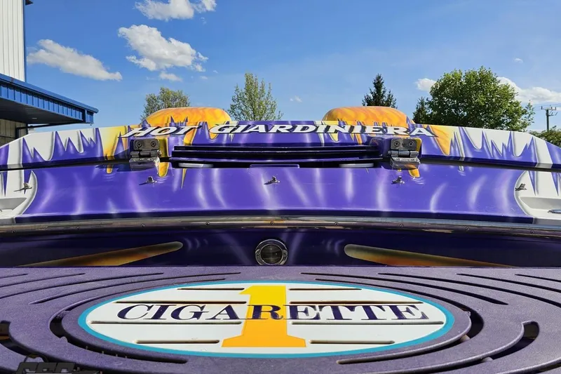 Slide: The Image of 2002 Cigarette 42' Tiger boat with vibrant purple and yellow design under a clear blue sky. - 41