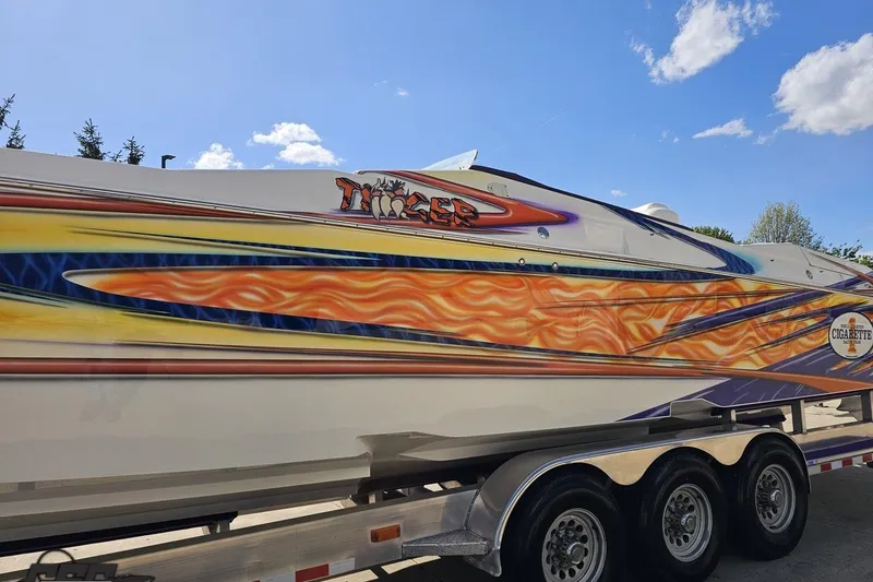 Slide: The Image of 2002 Cigarette 42' Tiger boat with vibrant flame graphics on a trailer. - 26