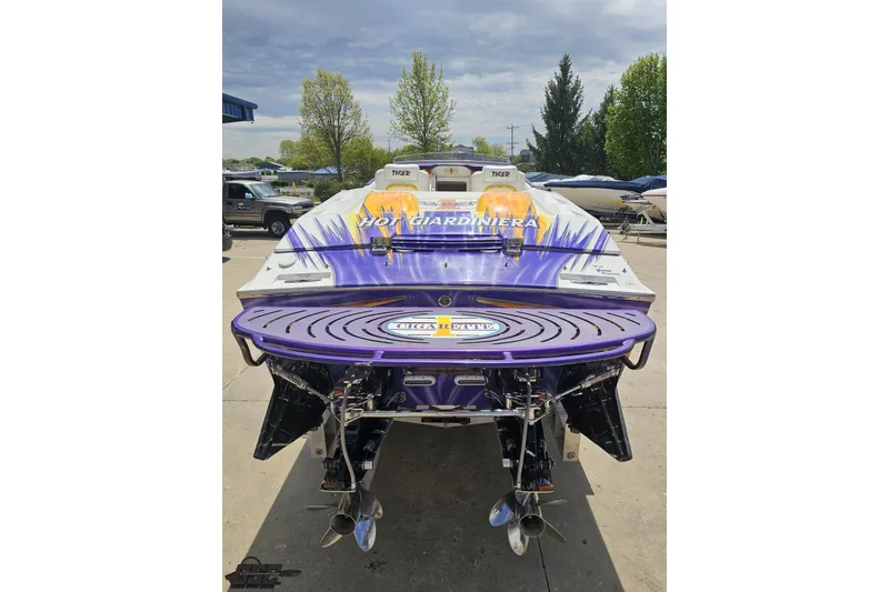 Slide: The Image of 2002 Cigarette 42' Tiger boat with vibrant purple and yellow design, docked outdoors. - 40