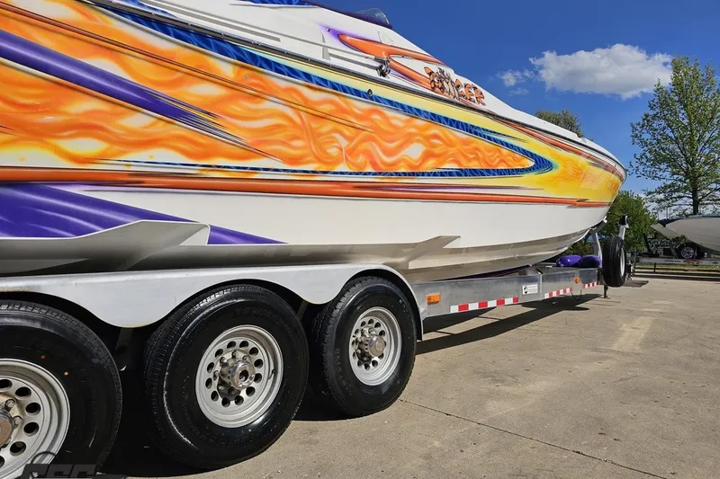Slide: The Image of 2002 Cigarette 42' Tiger boat with vibrant flame graphics on a trailer. - 13