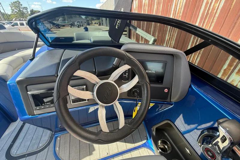 Slide: The Image of 2023 Manitou 25LXSHP boat dashboard with steering wheel and Garmin display. - 12