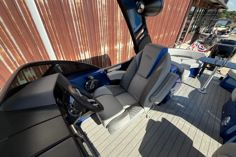 Slide: The Image of 2023 Manitou 25LXSHP boat interior with luxurious seating and modern steering console. - 6