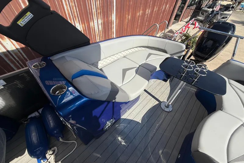 Slide: The Image of 2023 Manitou 25LXSHP pontoon boat interior with seating and table, featuring cup holders. - 11