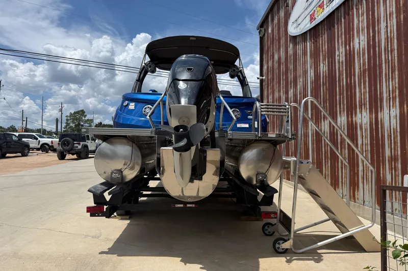 Slide: The Image of 2023 Manitou 25LXSHP pontoon boat with powerful outboard motor, parked outdoors. - 13