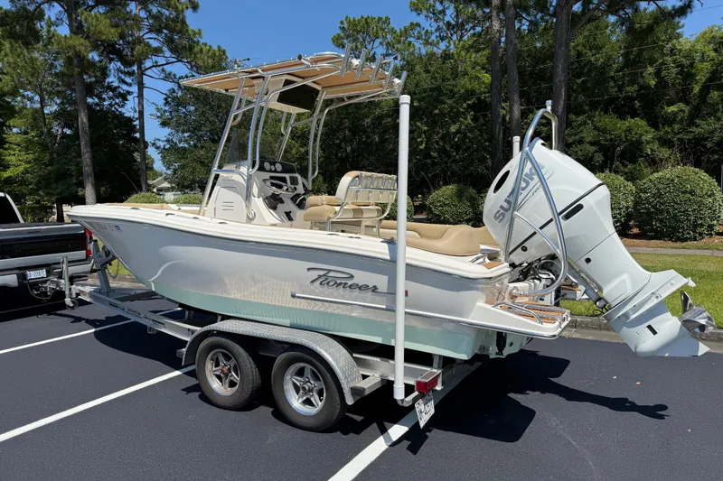 Slide: The Image of 2021 Pioneer 202 Islander boat on trailer with Suzuki outboard motor in parking lot. - 23