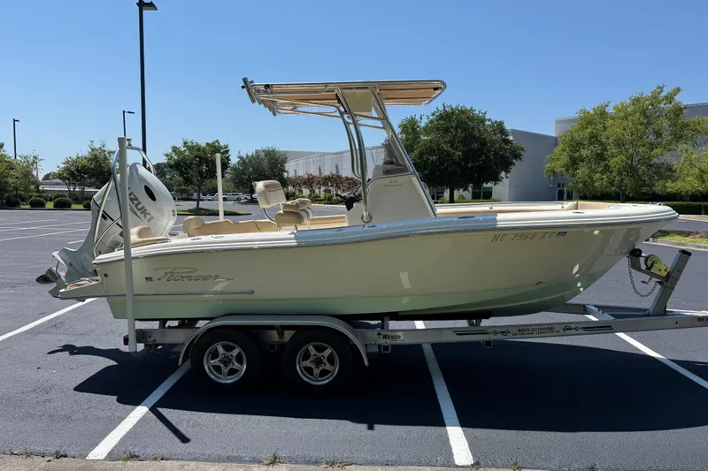 Slide: The Image of 2021 Pioneer 202 Islander boat on trailer in parking lot, featuring Suzuki outboard motor. - 32