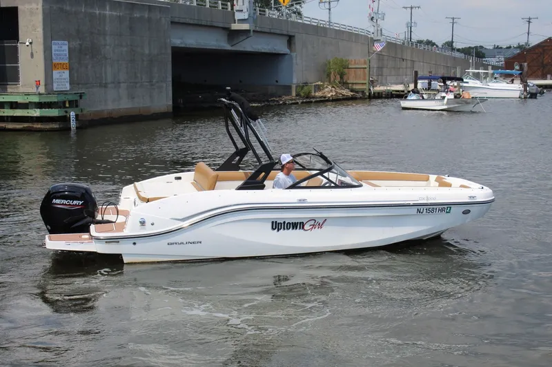 The Image of A 2022 Bayliner DX 2000 cruising on a river. It features a Mercury outboard motor. - 0