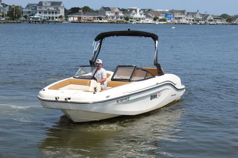 Slide: The Image of A 2022 Bayliner DX 2000 cruising on calm waters, with houses visible in the background. - 4
