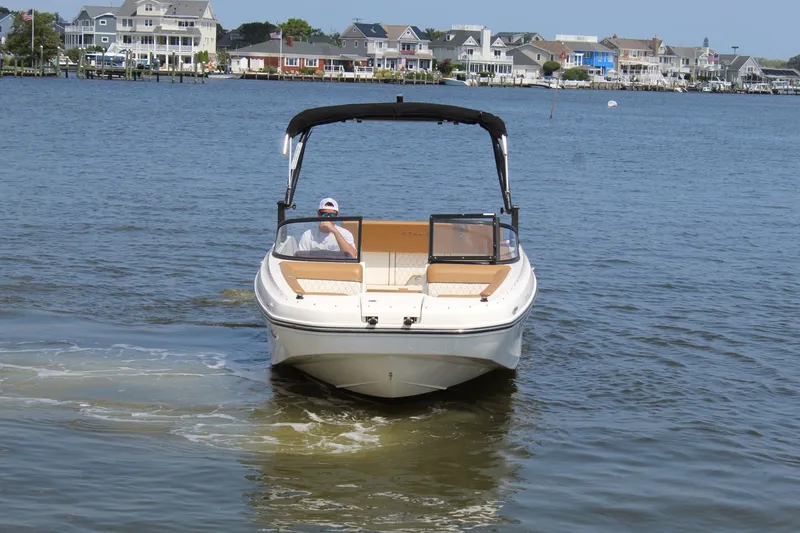 Slide: The Image of A 2022 Bayliner DX 2000 on calm waters, with houses visible in the background. - 3