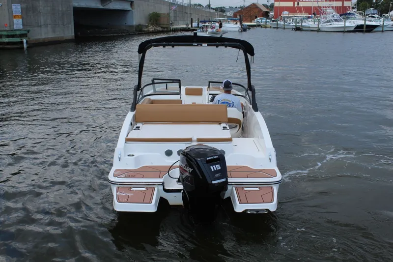 Slide: The Image of A 2022 Bayliner DX 2000 on a river. It features an outboard motor and beige seating. - 8