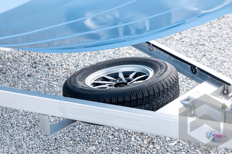 Slide: The Image of Spare tire under G3 Bay 19 GX boat trailer, 2026 model, on gravel surface. - 9