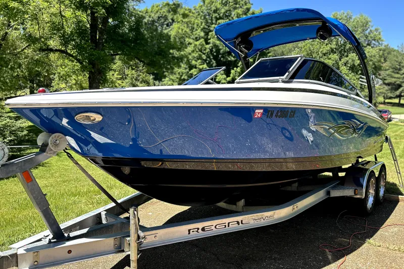 Slide: The Image of 2012 Regal 2300 RX Bowrider on trailer, blue hull, parked outdoors. - 1