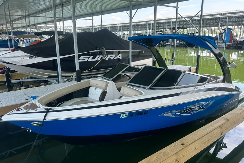 Slide: The Image of 2012 Regal 2300 RX Bowrider in marina, blue hull, sleek design, covered dock. - 2