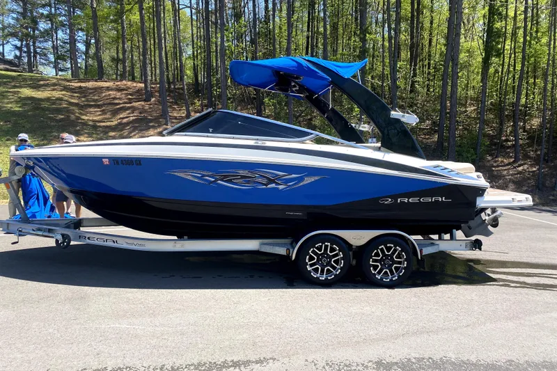 The Image of 2012 Regal 2300 RX Bowrider on trailer, parked near wooded area. - 0