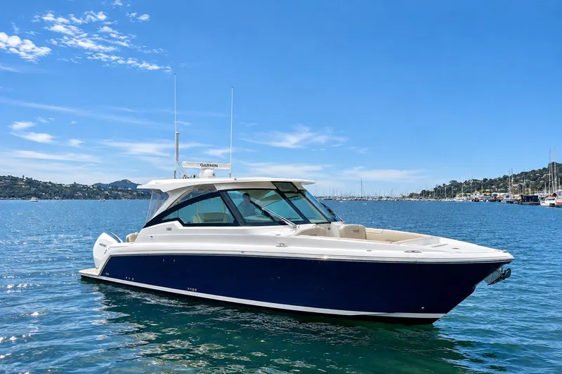 The Image of 2027 Tiara Yachts 34 LX cruising on a sunny day in a scenic harbor. - 0