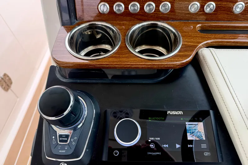 Slide: The Image of Tiara Yachts 34 LX 2027 dashboard with controls, cup holders, and Fusion Bluetooth system. - 27