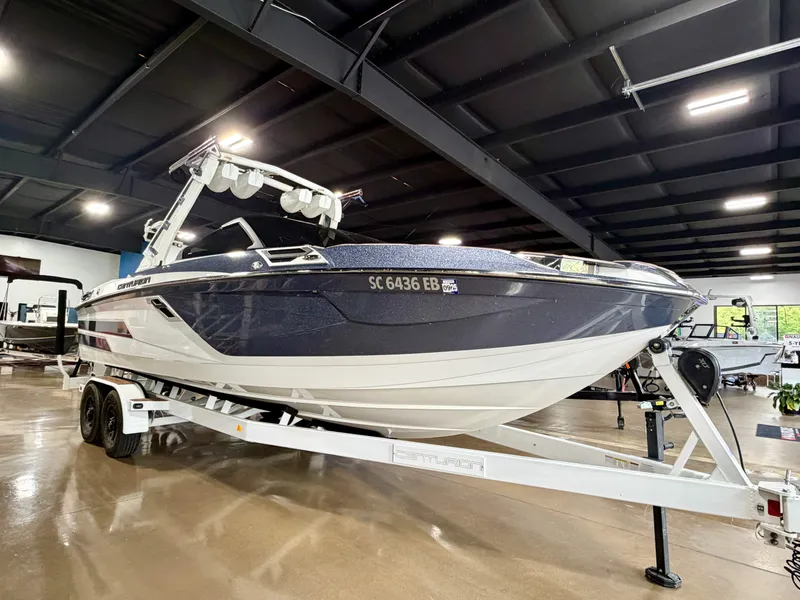 Slide: The Image of A 2022 Centurion Ri245 boat is on a trailer inside a showroom. - 7