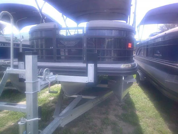 Slide: The Image of A 2024 Bennington 23RSB Swingback Tritoon on a trailer, surrounded by other boats. - 12