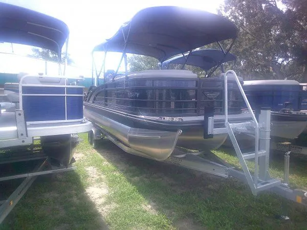 The Image of A 2024 Bennington 23RSB Swingback Tritoon on a trailer, surrounded by other boats. - 1