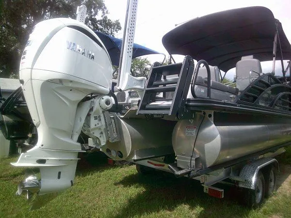 Slide: The Image of A 2024 Bennington 23RSB Swingback Tritoon on a trailer. The outboard motor is visible. - 10