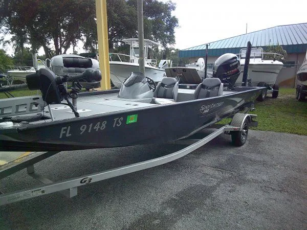 The Image of A gray 2022 G3 Sportsman 1810 boat on a trailer. It features an outboard motor. - 1