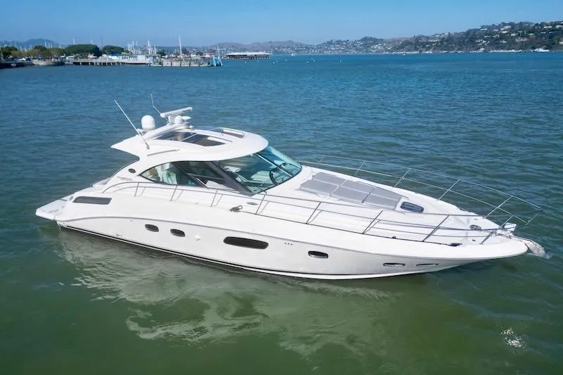 Slide: The Image of 2010 Sea Ray 470 Sundancer yacht on calm water, scenic coastal background. - 3
