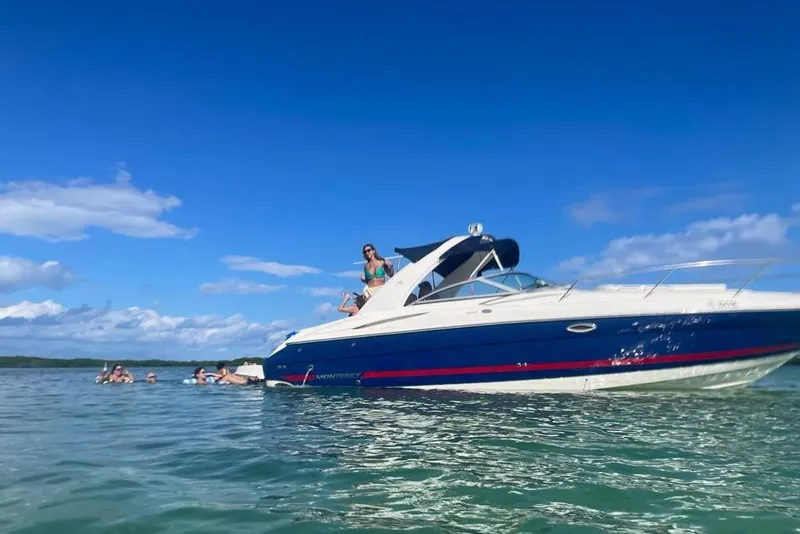 The Image of 2006 Monterey 298SC Super Sport boat on water, people swimming nearby under clear blue sky. - 0